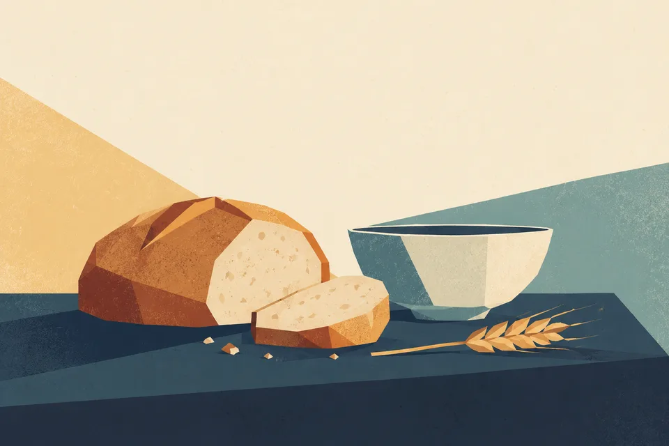 A loaf, a slice of bread and a bowl on a table.